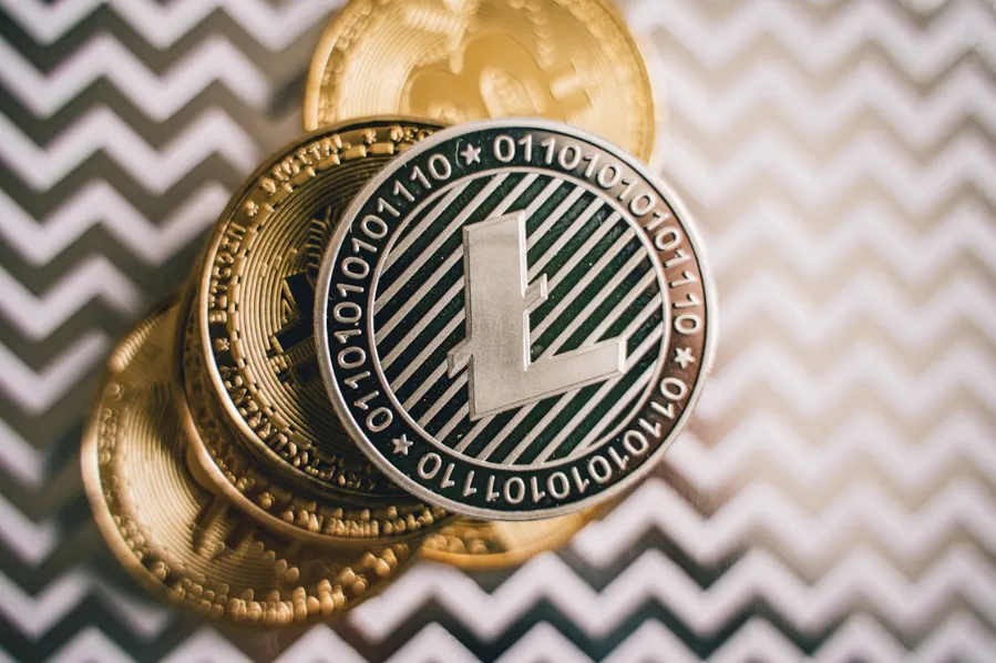 Close-up of Litecoin coin stacked with other cryptocurrencies on a patterned background, symbolizing LTC’s growth potential