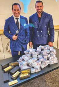 Josip Heit posing with stacks of cash and gold bars at an event