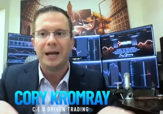 Cory Kromray speaking in front of trading monitors as CEO of Driven Trading