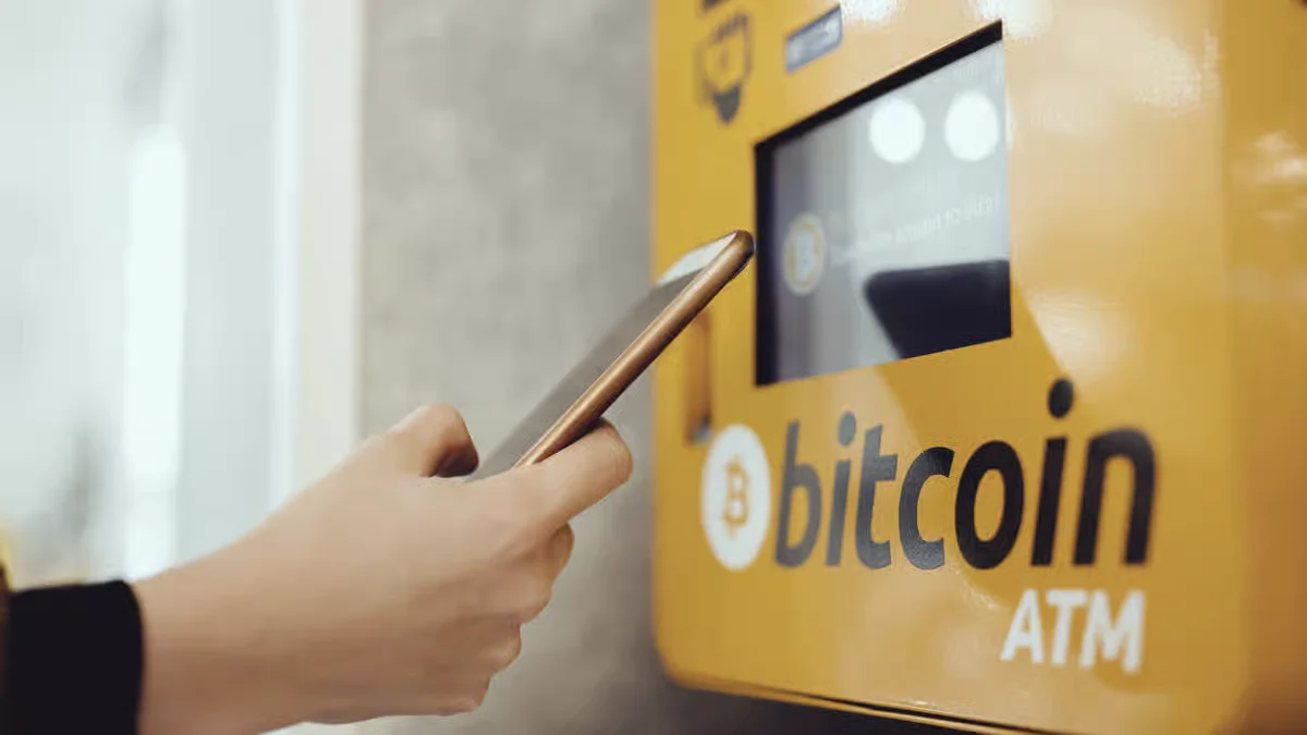 Person using a smartphone with Bitcoin ATM for cryptocurrency transaction