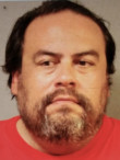 Booking mugshot of Konstantin Ignatov, leader and co-founder of the OneCoin cryptocurrency pyramid scheme, wearing a red shirt after his arrest by US authorities.