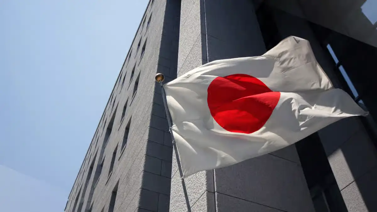 Japanese flag outside a building representing Lawson testing JPYC stablecoin payments in Japan.