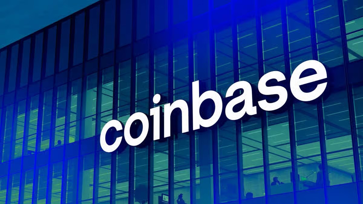 Exterior of the Coinbase corporate office building, featuring a large white 3D logo on a modern glass facade with a blue and green color overlay.