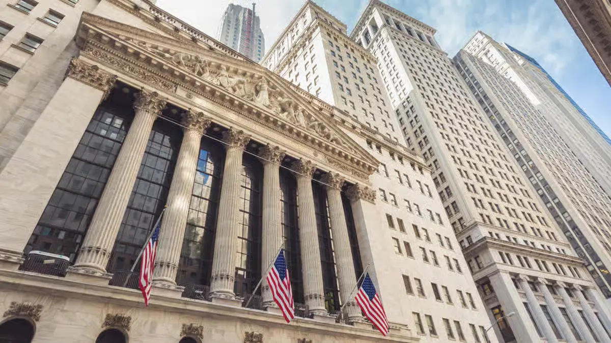 New York Stock Exchange building on Wall Street with American flags