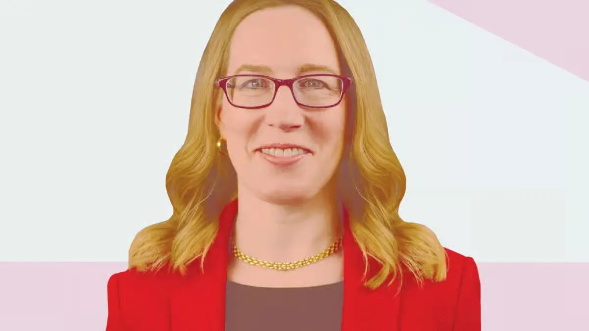 Professional woman with glasses and red blazer smiling against a light background