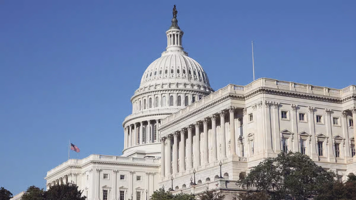 Low-angle exterior view of the iconic United States Capitol building and dome under a clear blue sky in Washington DC.