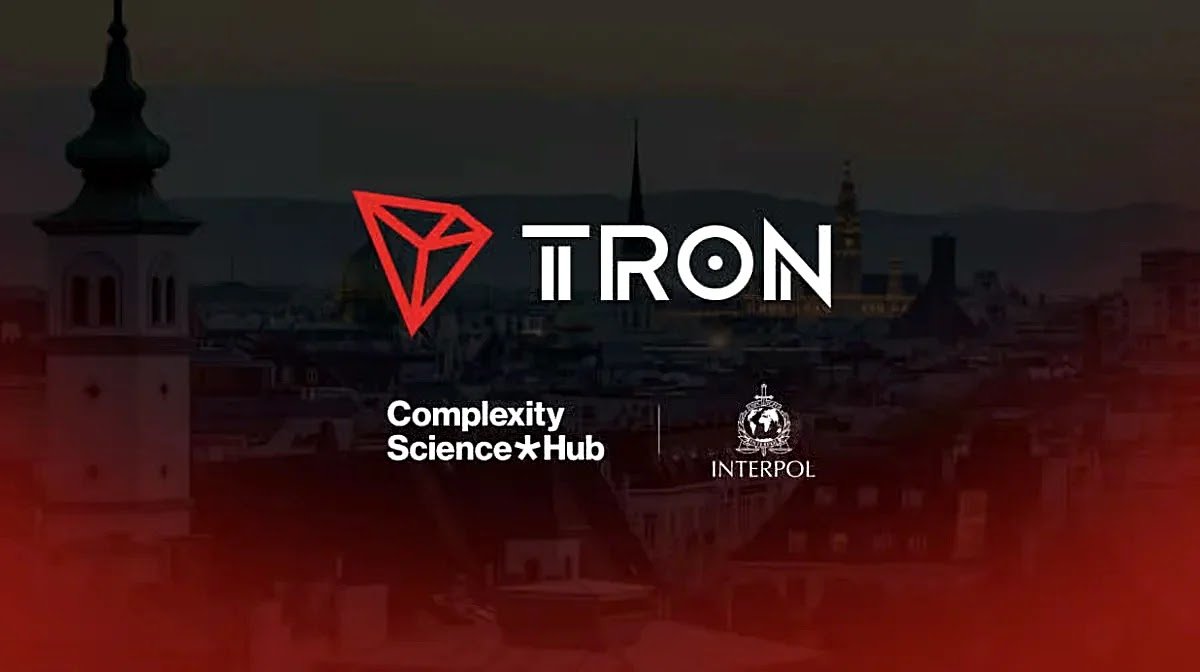 TRON logo displayed alongside Complexity Science Hub and Interpol logos over a European city skyline background.